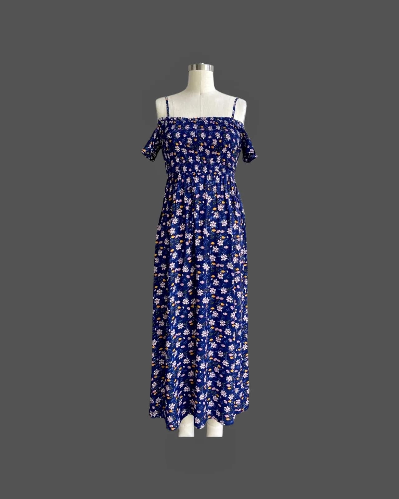 Front view of a navy floral off-shoulder smocked floral maxi dress on a dress form