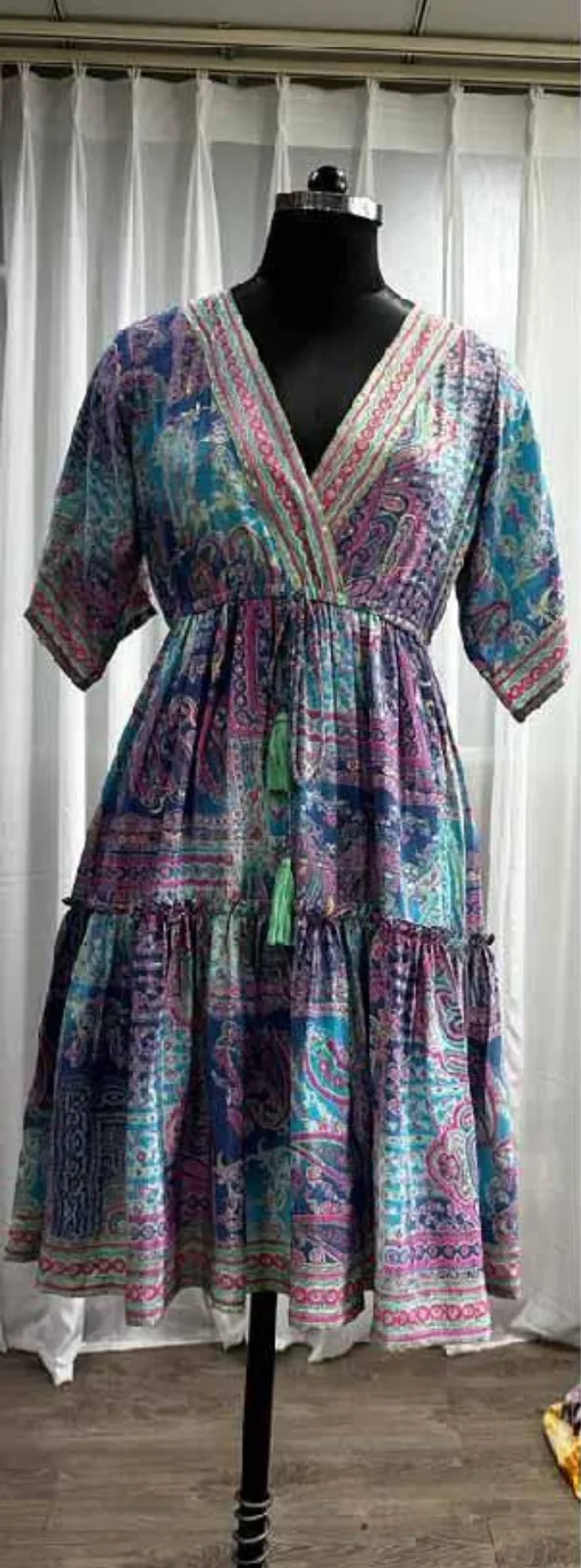 Front view of a blue, pink and green paisley foil-print kaftan dress with tie waist on a dress form