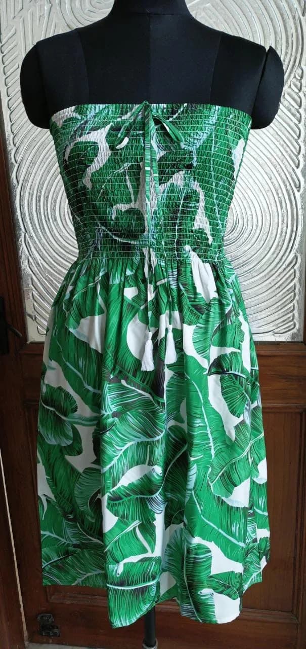 Front view of a green palm print smocked strapless mini sundress on a dress form